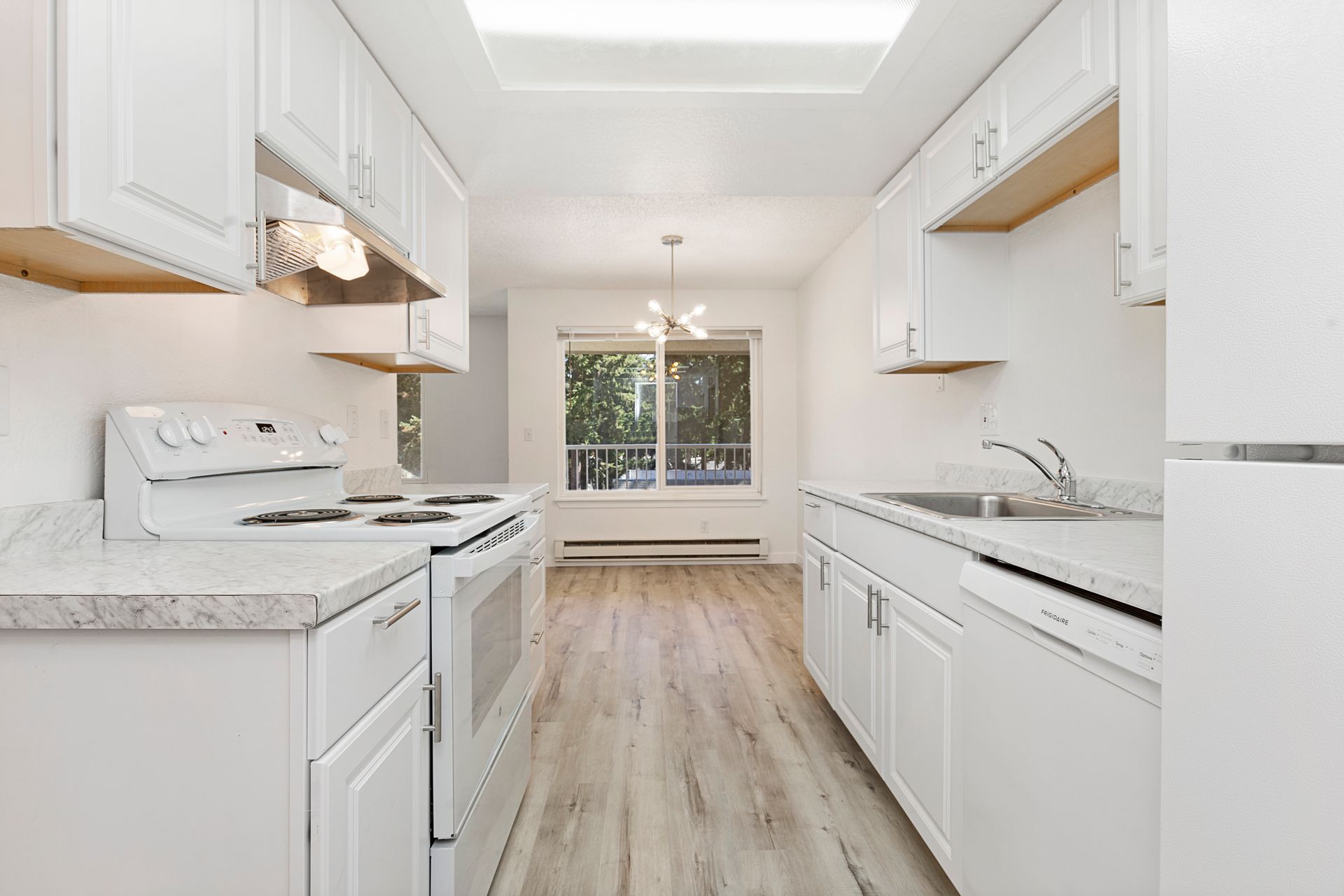 a kitchen with white cabinets , a stove , a refrigerator , and a sink .