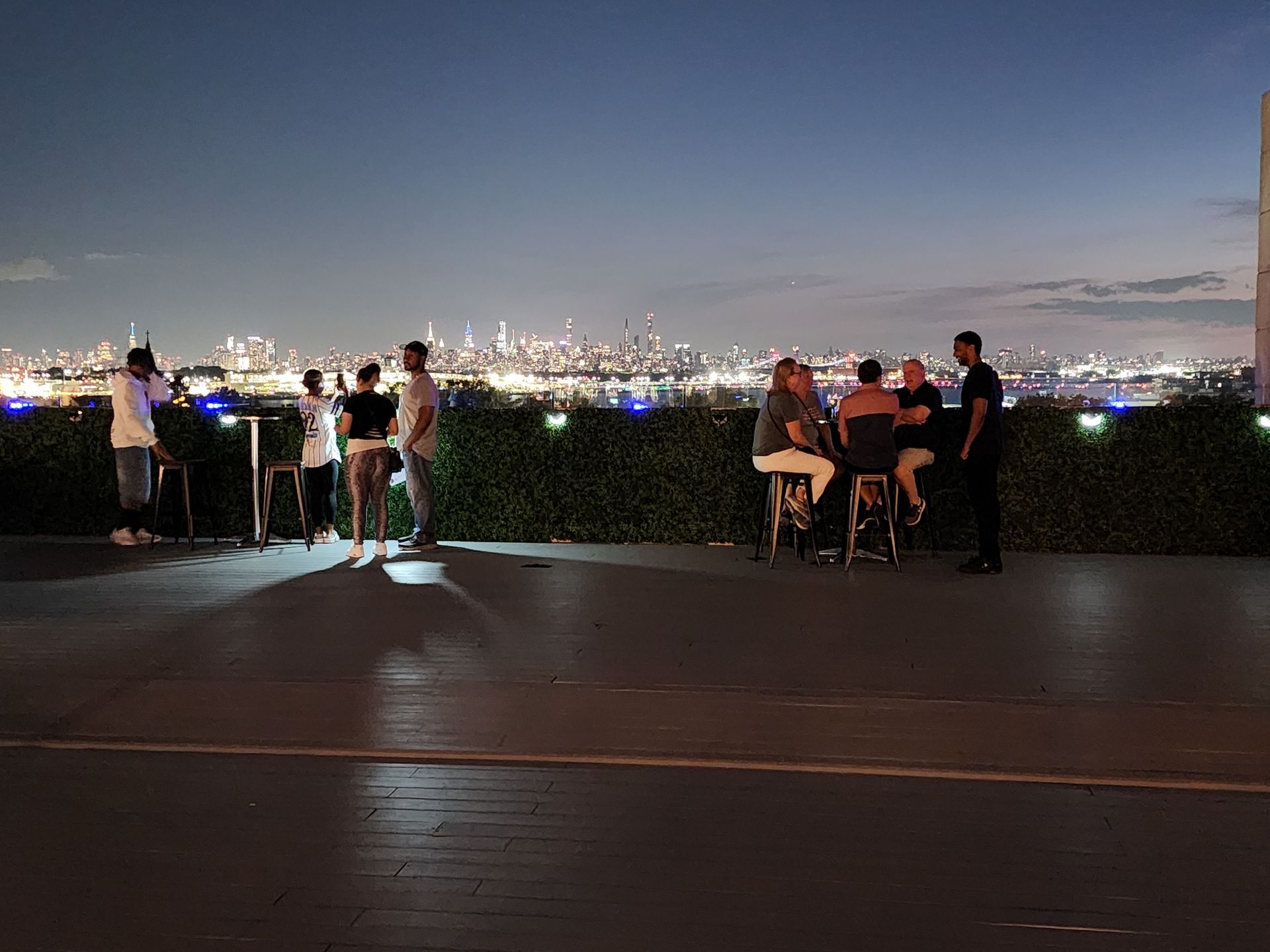 A group of people are sitting at tables on a rooftop at night.