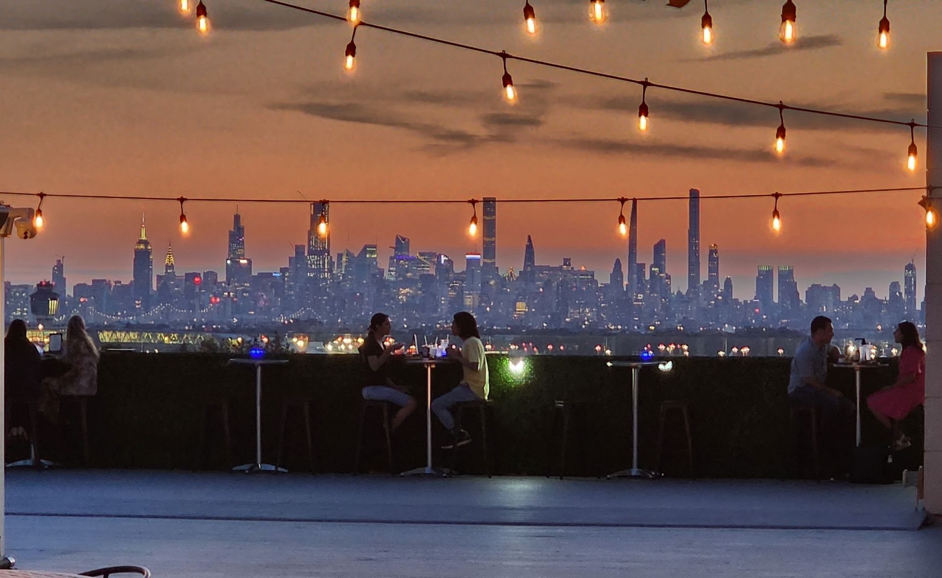 People sitting at tables with a view of the city skyline