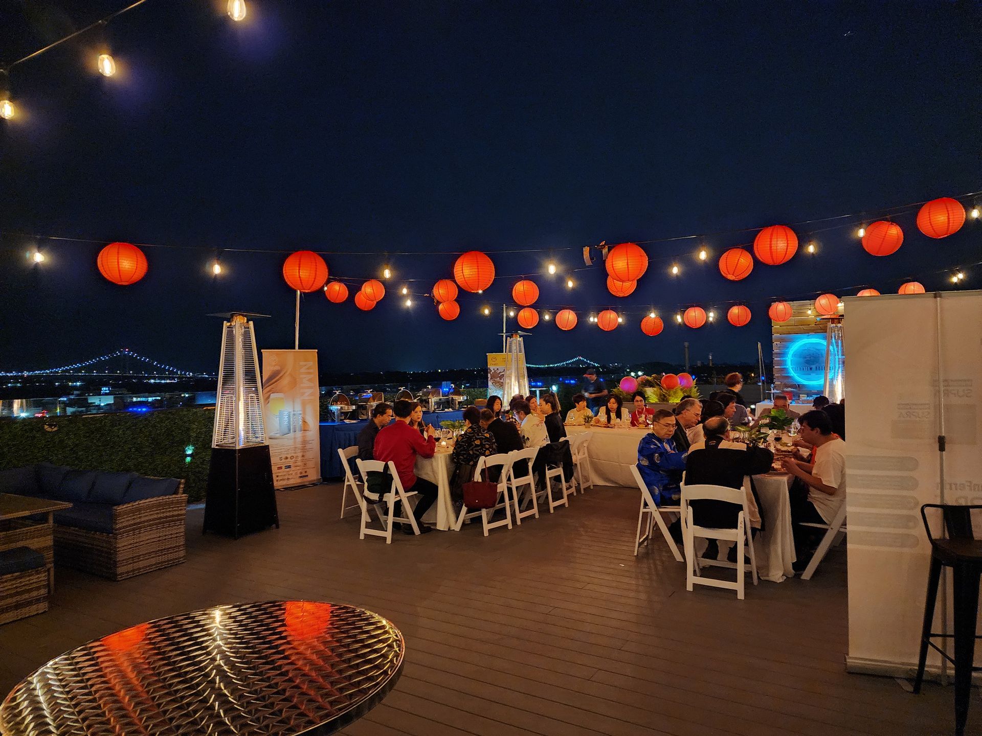 A group of people are sitting at tables with lanterns hanging from the ceiling.