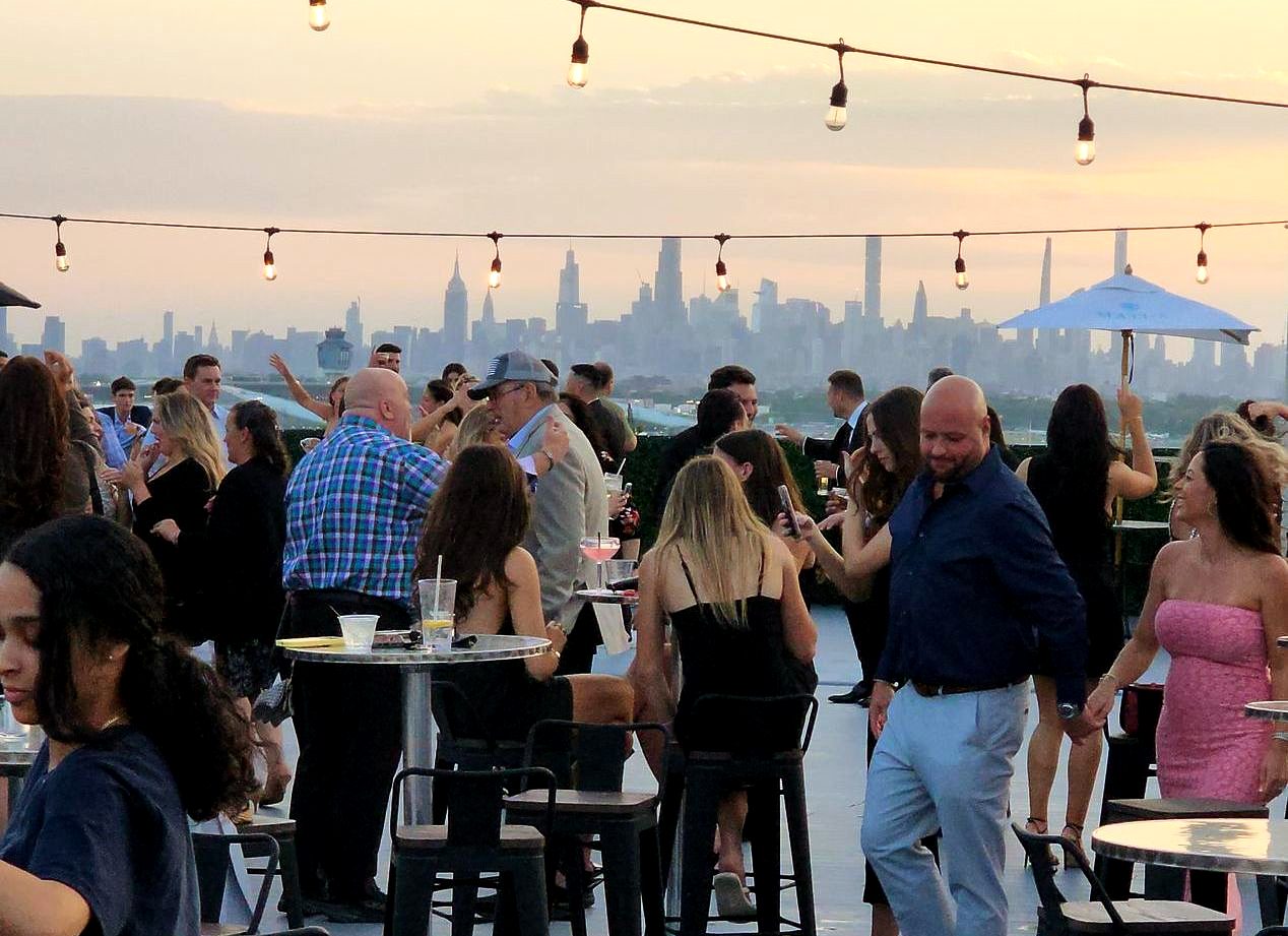 People at rooftop party with new york city skyline background.