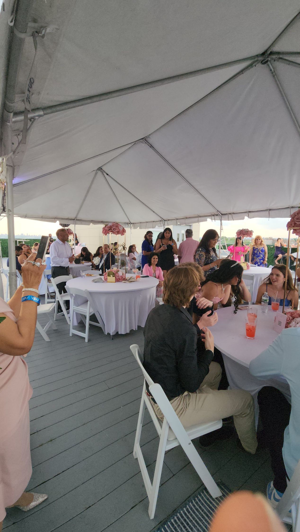 People seated at tables under a white tent; a social gathering.