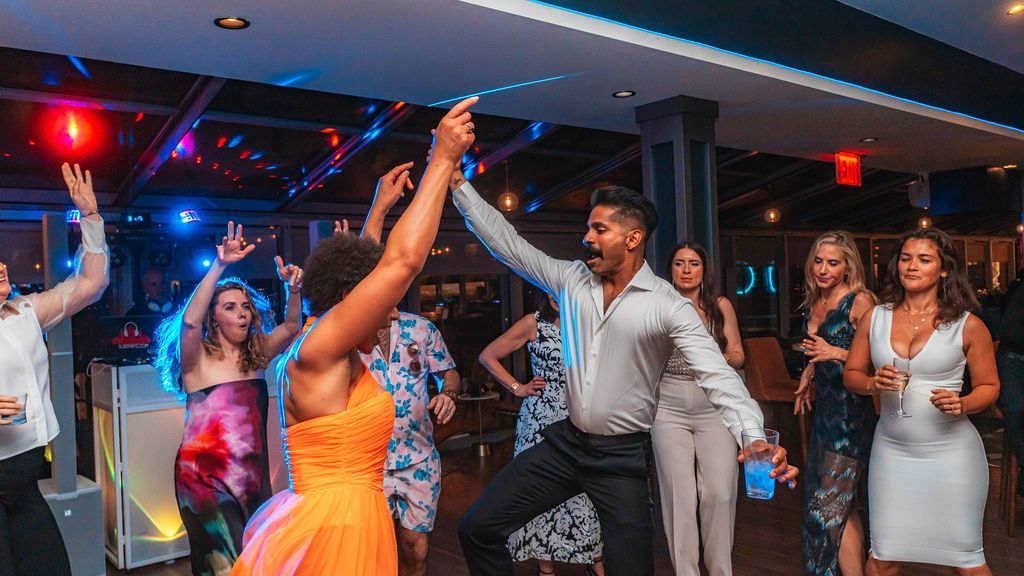 People dancing joyfully at a party with colorful lights.
