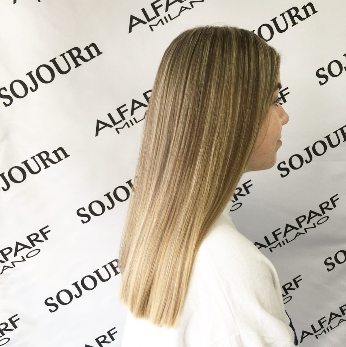 A woman is standing in front of a wall that says sojourn