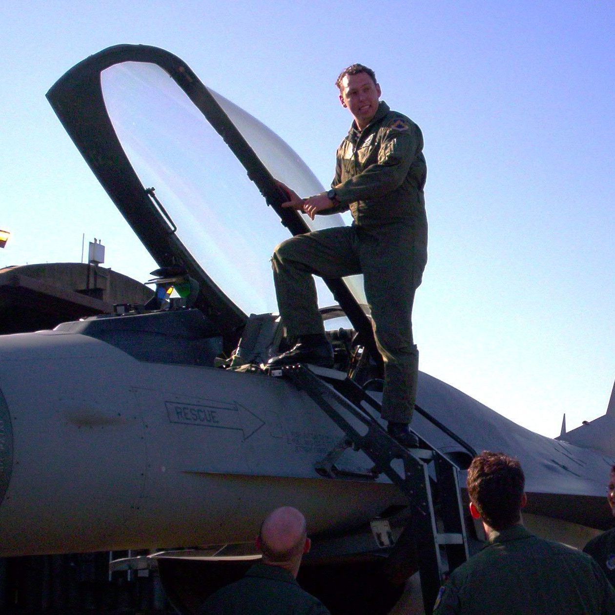 A man stands on top of a fighter jet with the letters n82 on the side