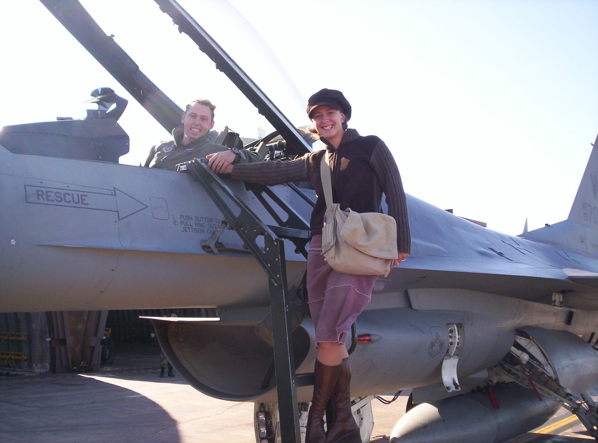 A woman stands next to a fighter jet with the word rescue on the side