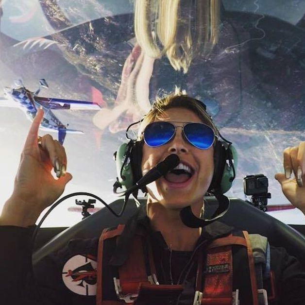 Grinning passenger in the cockpit of a Sky Combat Ace stunt plane mid-flight