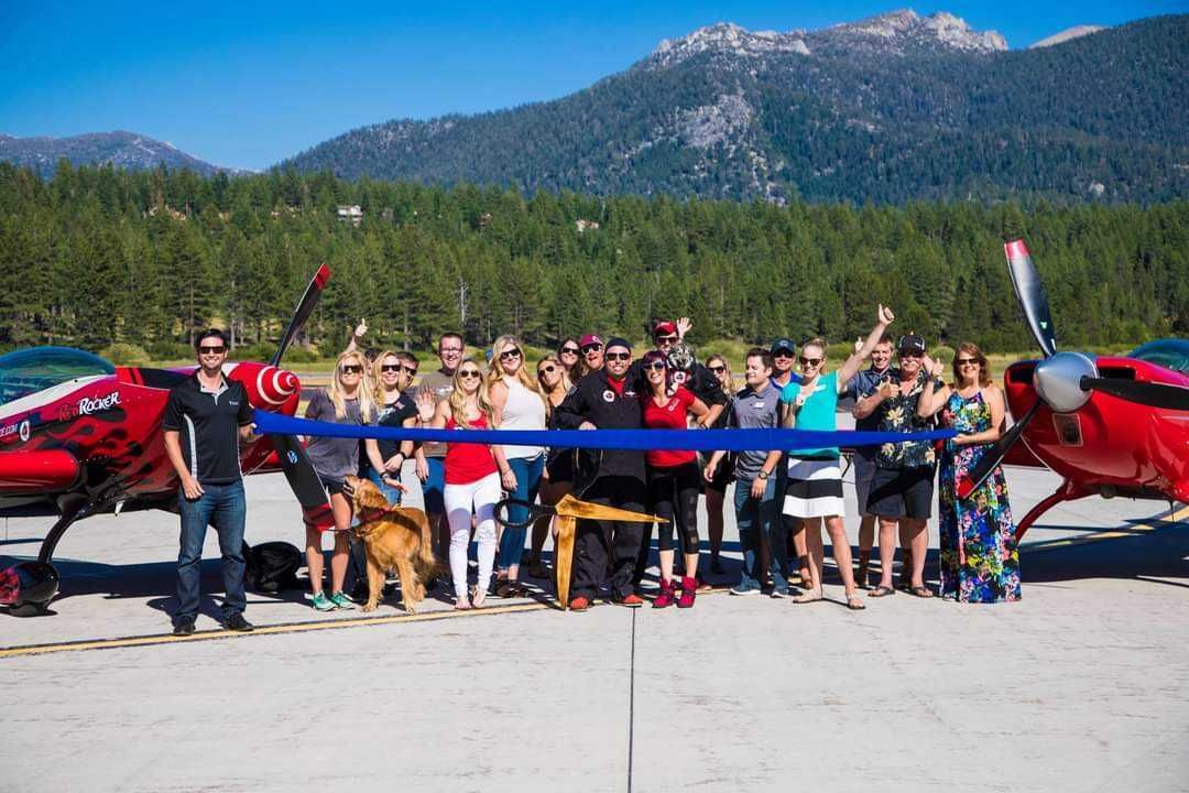 A group of people are standing in front of a red airplane.