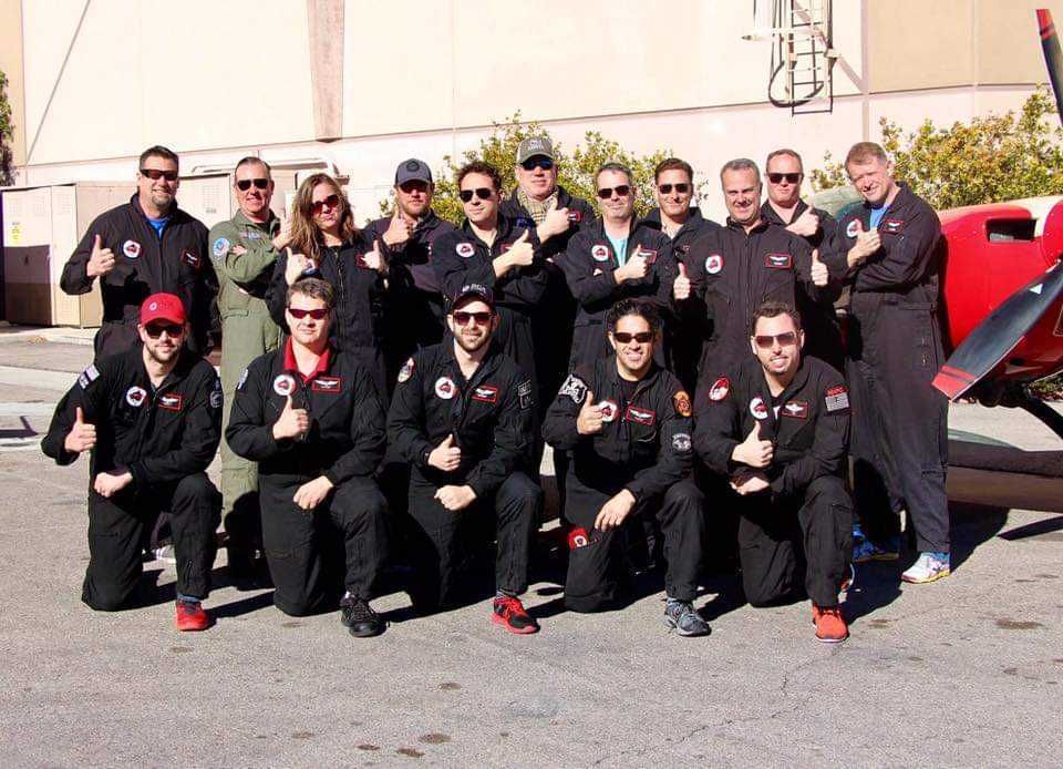 A group of people posing for a picture in front of a red plane