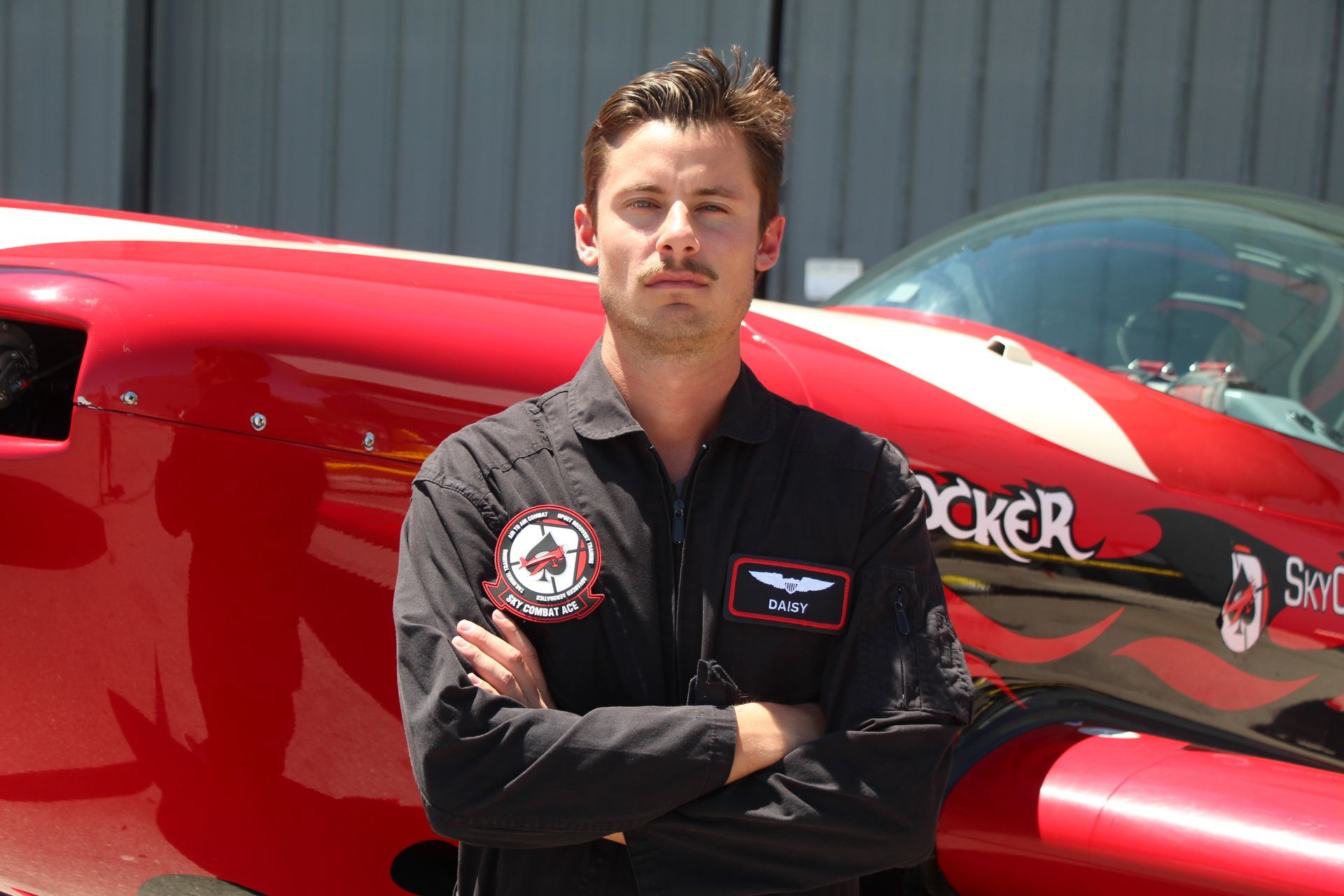 A man is standing in front of a red plane that says rocker on it