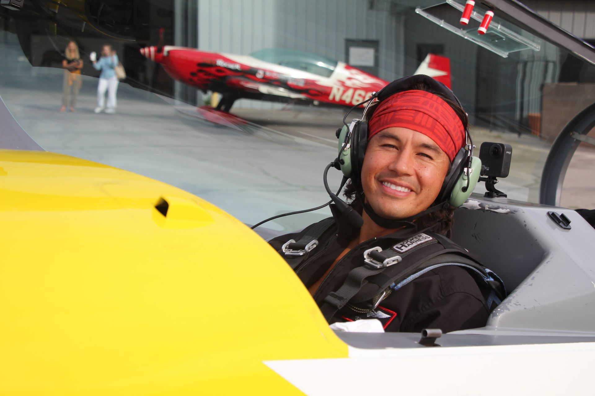 A man wearing headphones is sitting in the cockpit of an airplane.