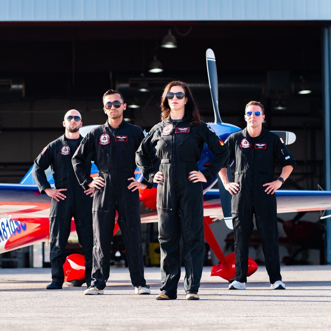 A group of pilots standing in front of an airplane