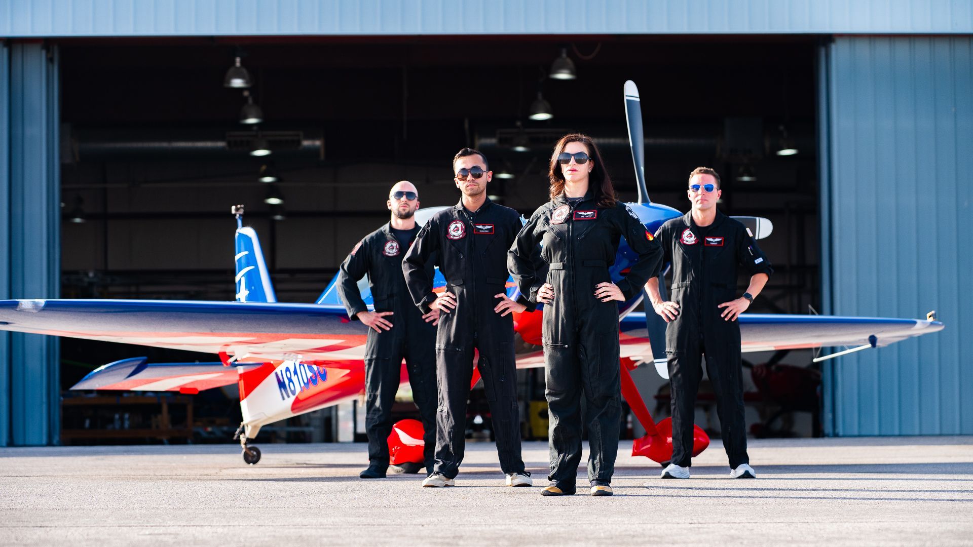 A group of people standing in front of an airplane in a hangar.