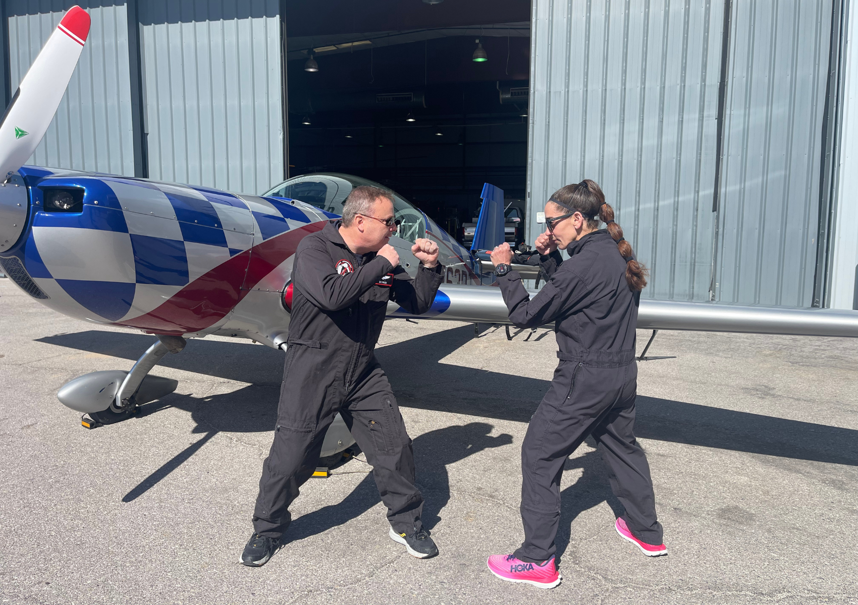 A man and a woman are standing in front of an airplane.