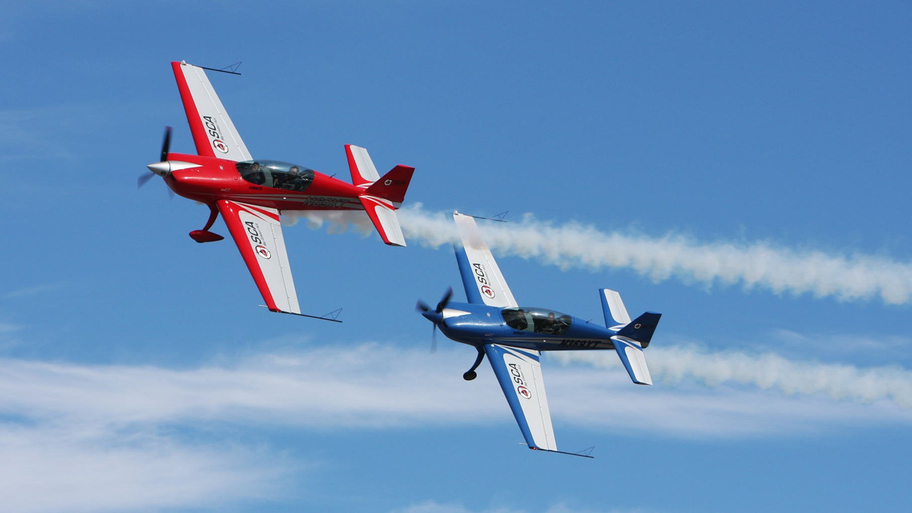 Two aircraft in formation against a blue sky