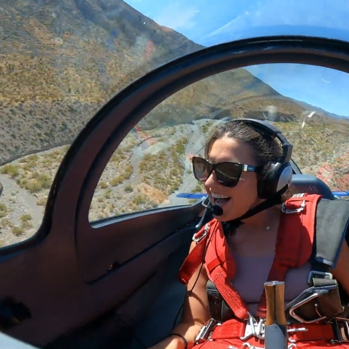 A woman wearing sunglasses and headphones is sitting in a plane
