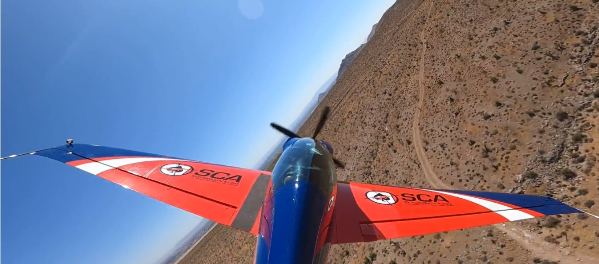 A blue and red airplane is flying over a mountain.