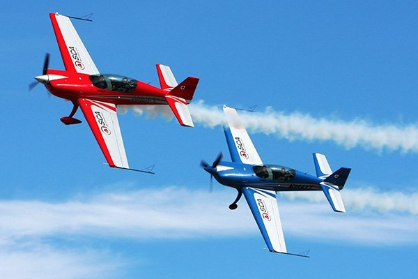 Two red and blue airplanes are flying in the sky