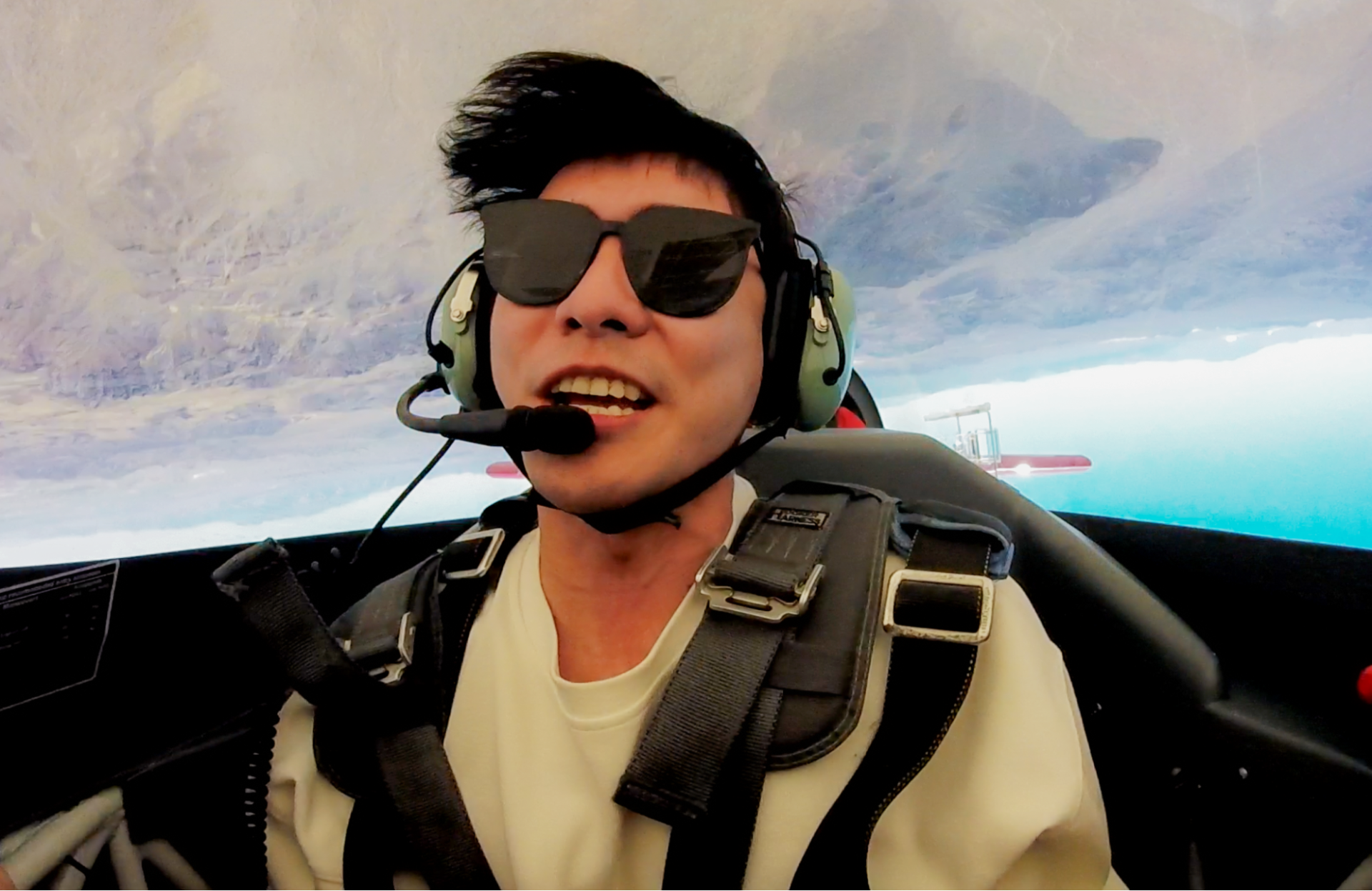 A man wearing sunglasses and headphones is sitting in a plane
