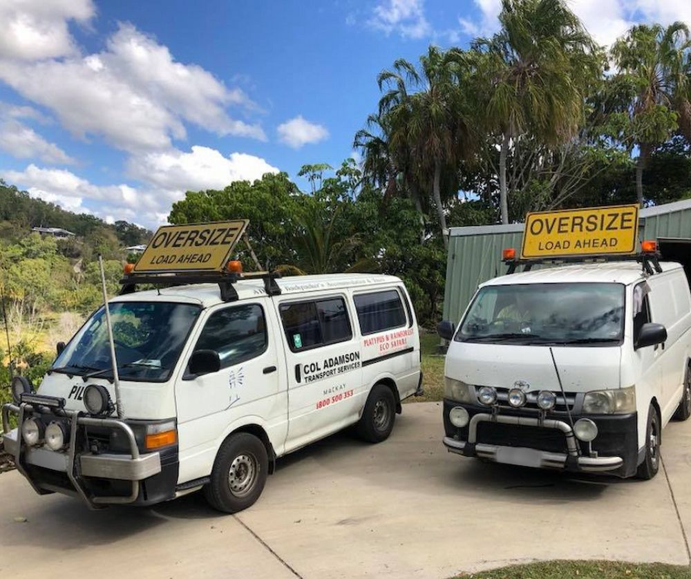 Two White Pilot Escort Vans Are Parked Next to Each Other — Col Adamson Transport Services in Farleigh, QLD