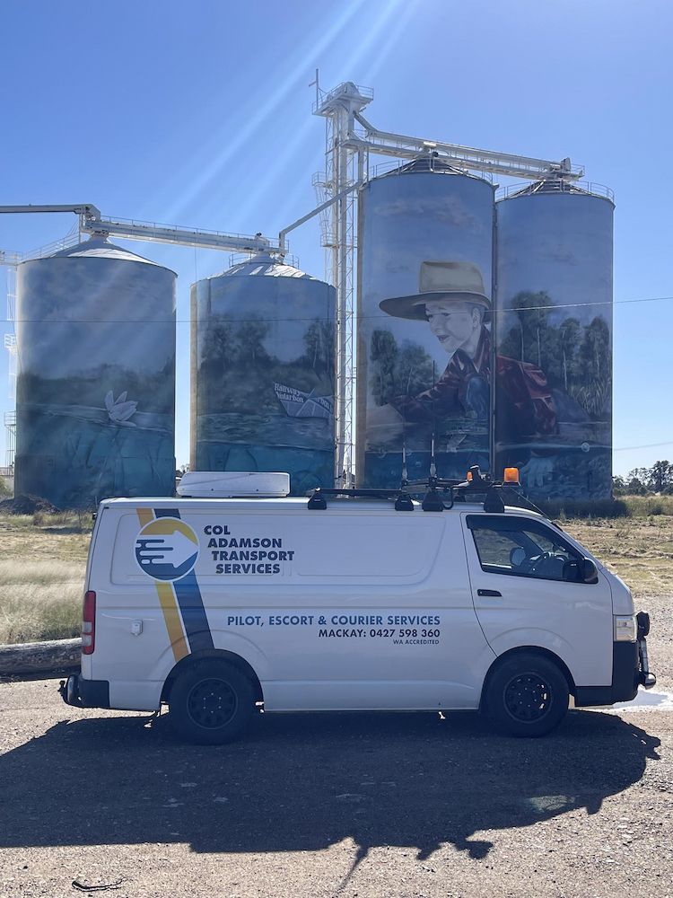 A White Van in Front of Grain Silos Painted With Mural — Col Adamson Transport Services in Farleigh, QLD