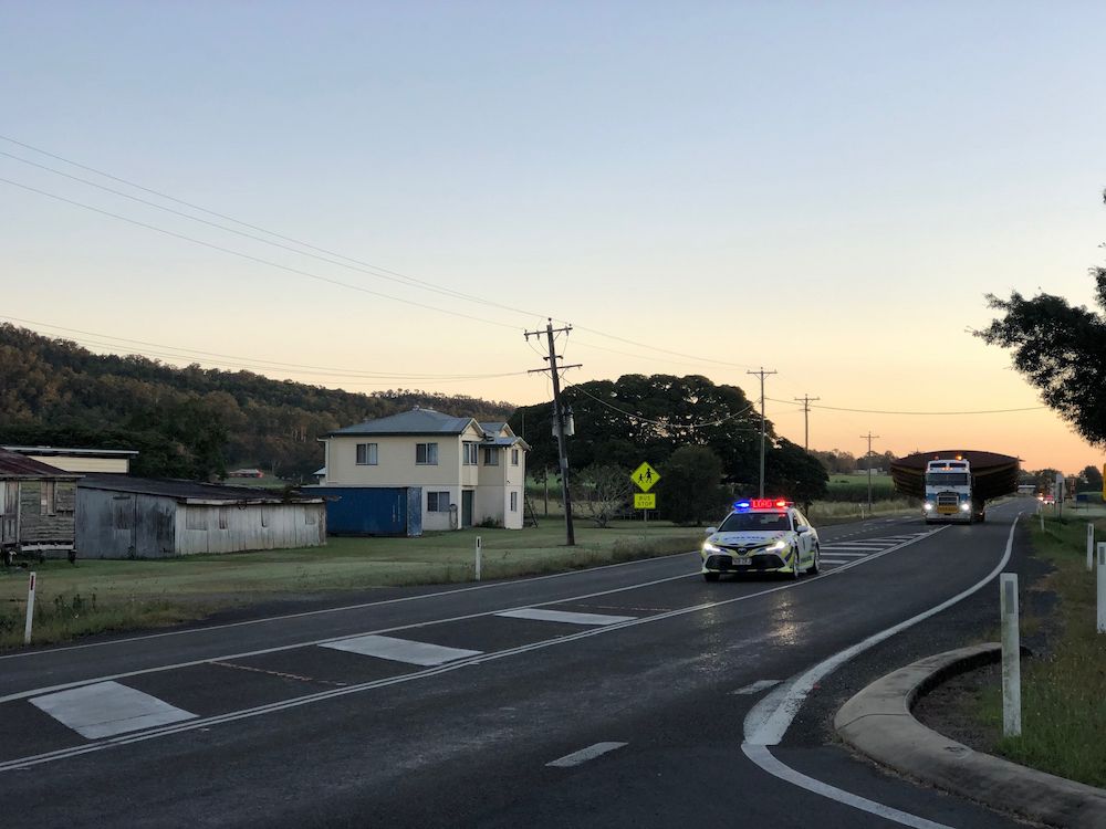 A Police Car and Large Semi Truck Are Driving Down the Road — Col Adamson Transport Services in Farleigh, QLD