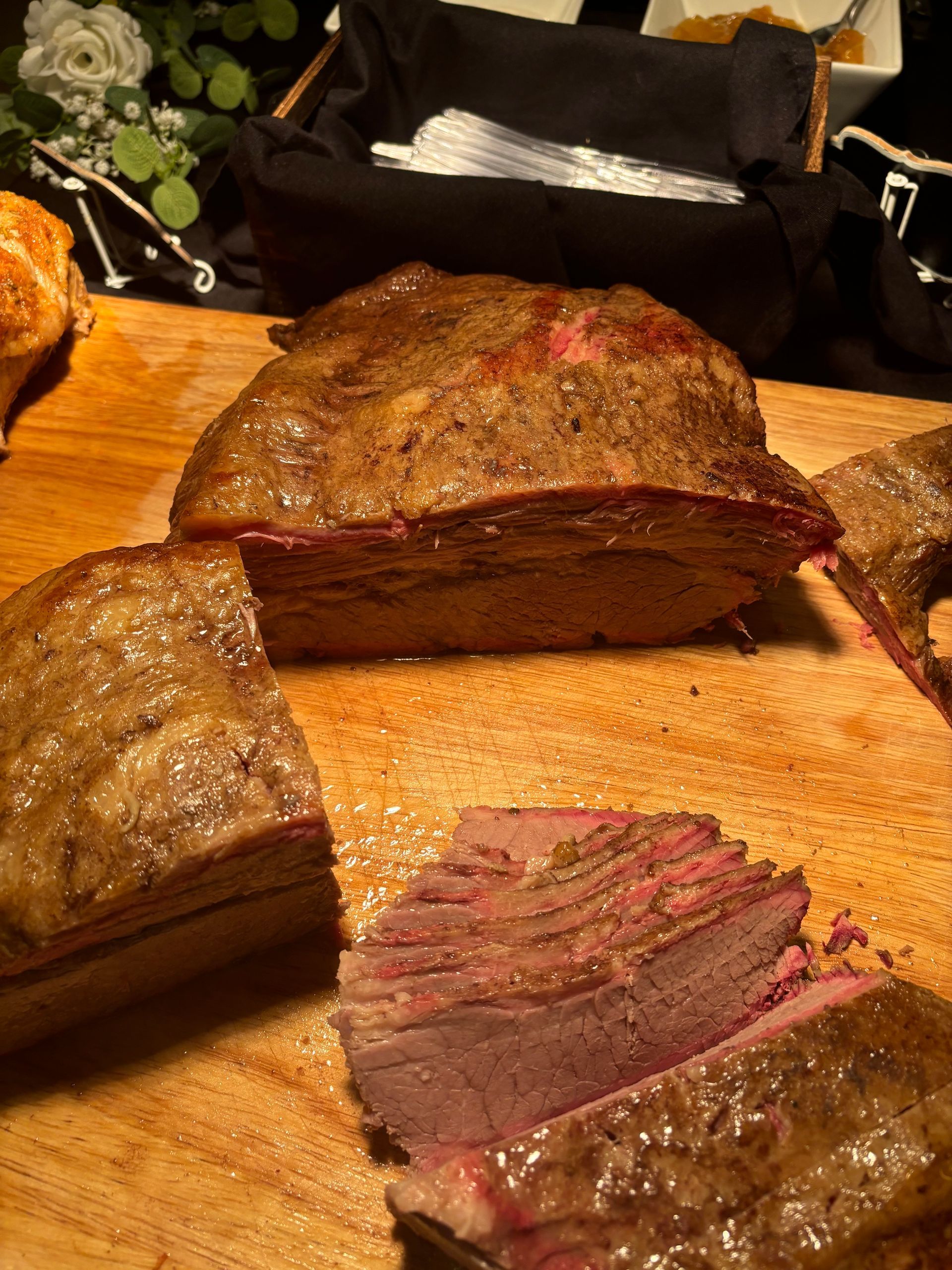 Sliced brisket on a wooden cutting board, showing the pink interior and crispy exterior.