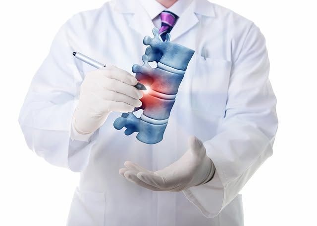Doctor holding a glowing blue spine model and pointing with a pen in a white lab coat