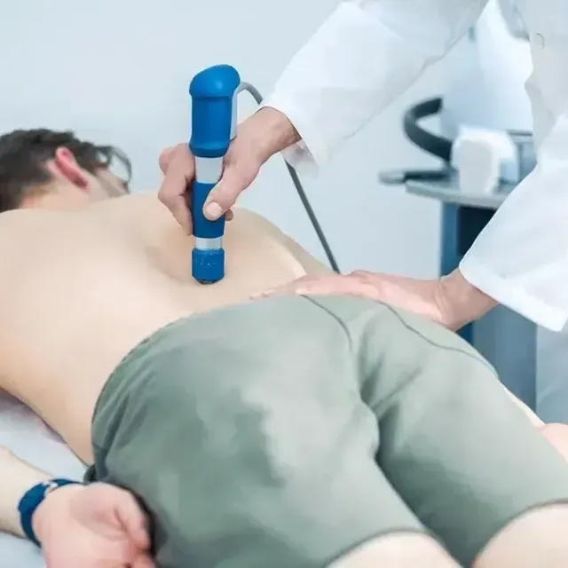 Medical provider using a handheld device on a patient lying face down on an exam table