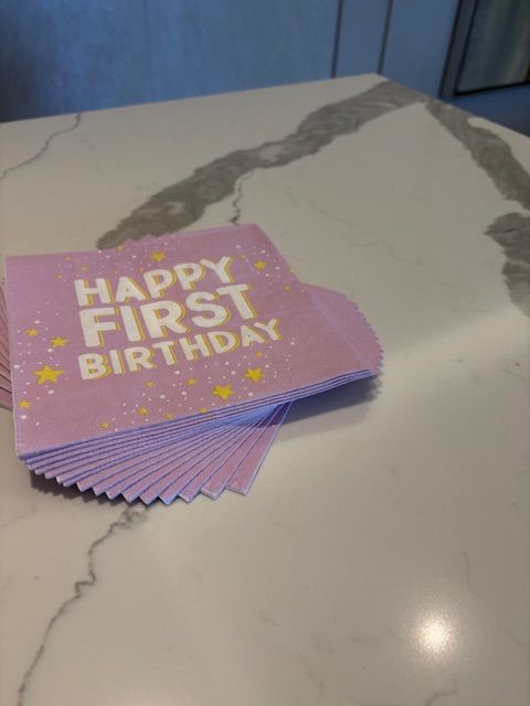 Pink paper napkins that reads Happy First Birthday.