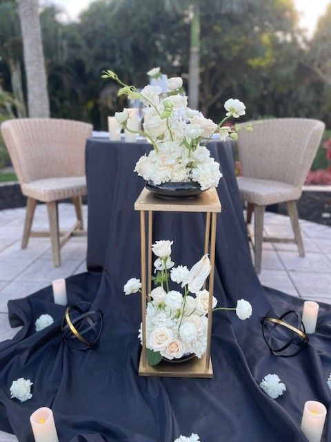 A picnic table next to the pool with white flowers and candles. Curated by An Elegant Picnic in South Florida.