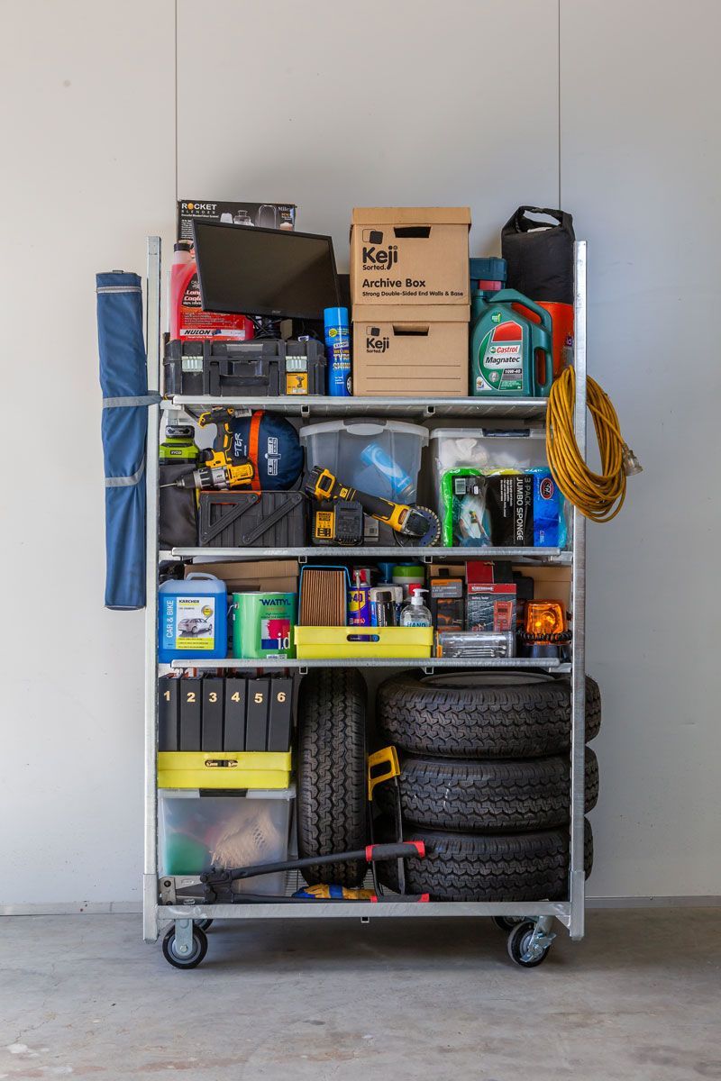 A cart filled with lots of tools and tires in a garage.