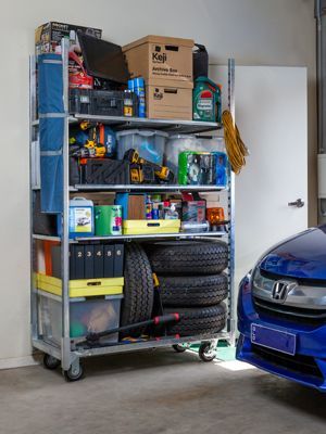 A blue car is parked next to a shelf in a garage.