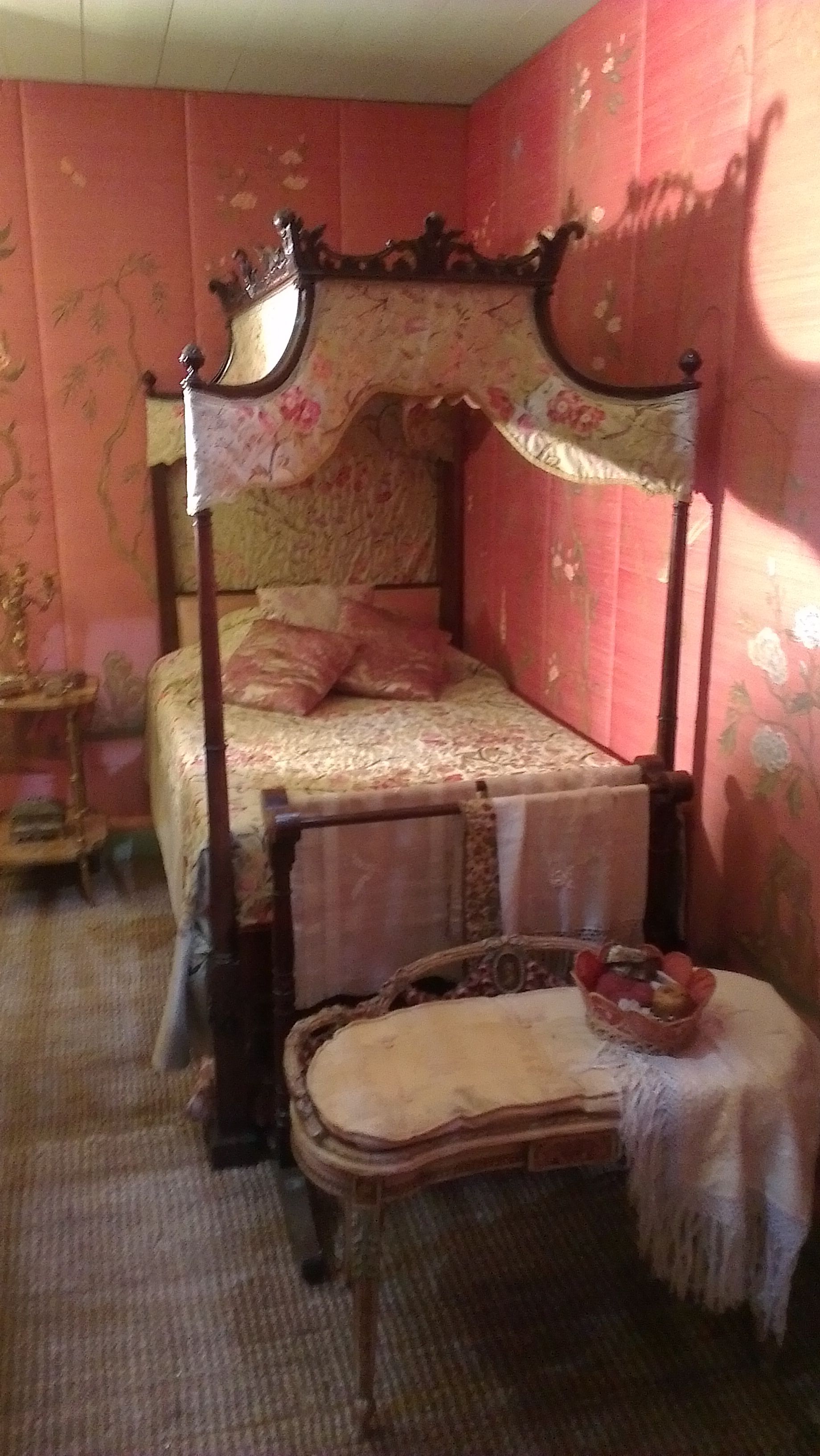 Pink bedroom with upholstered walls and four poster bed.