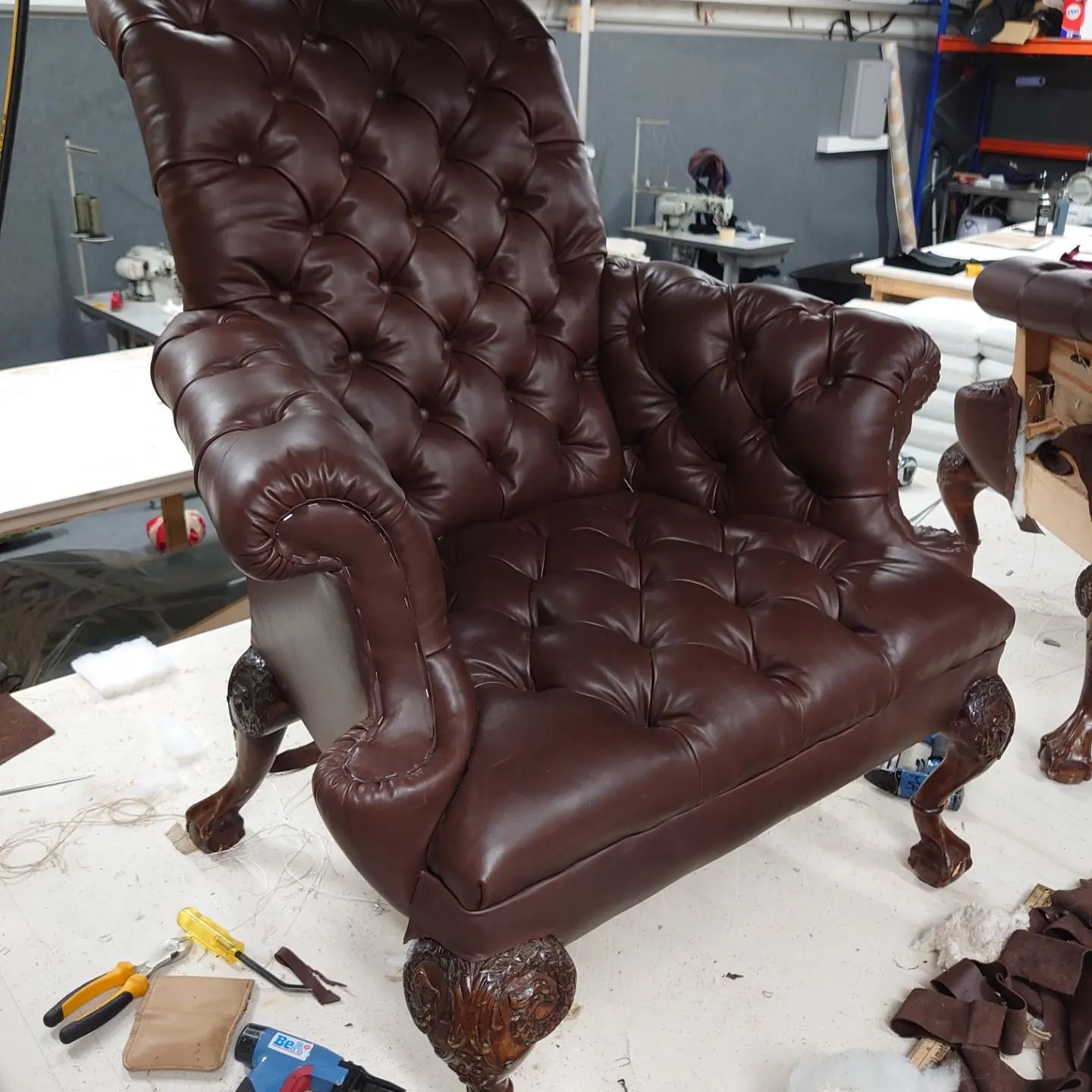 A deep buttoned, brown, leather, wing back chair.