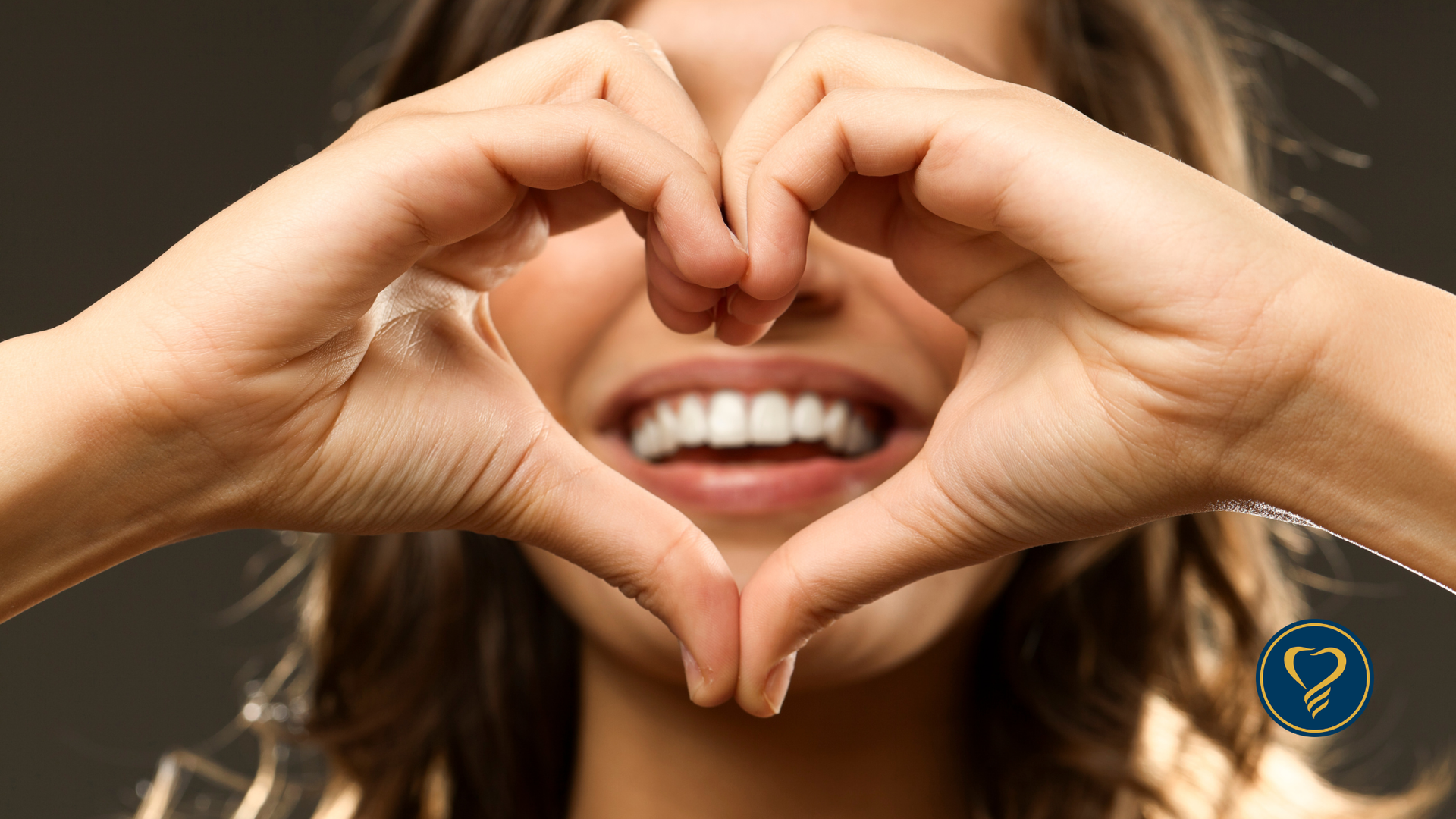 A person smiles while forming a heart shape with their hands in front of their face.