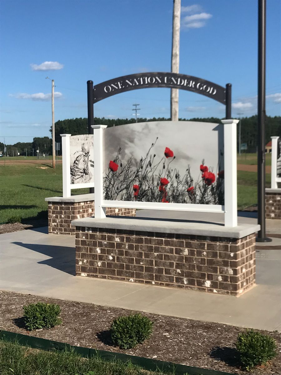 Memorial sign with brick base, white posts, poppy art, and the words 