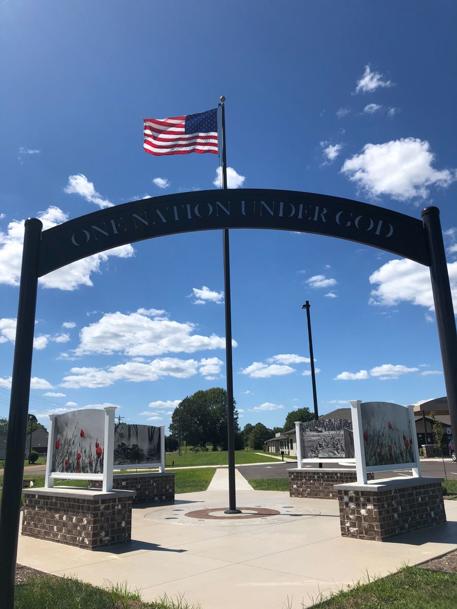 American flag flying above a memorial archway with 
