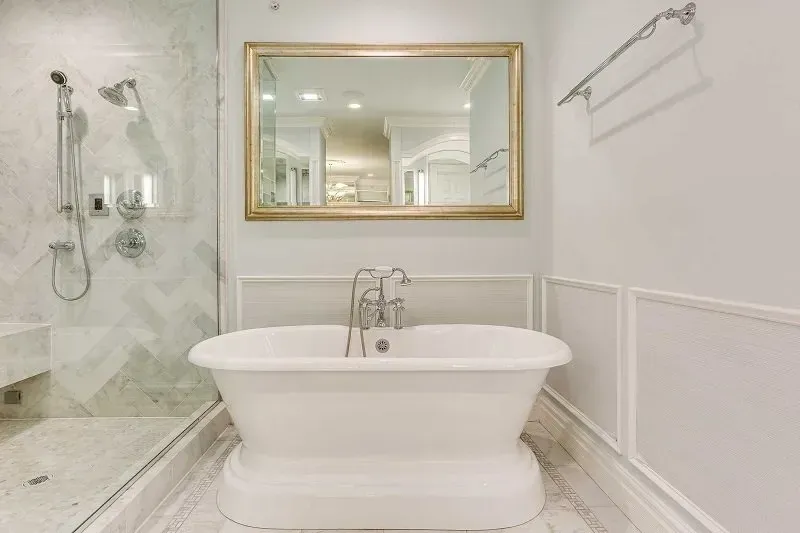 A bathroom with a bathtub , shower , and mirror.