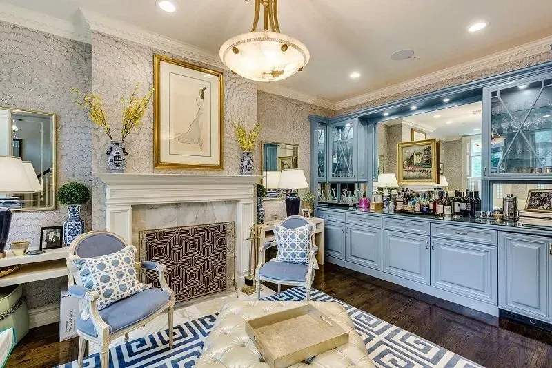 A living room with a fireplace , chairs , and a bar.