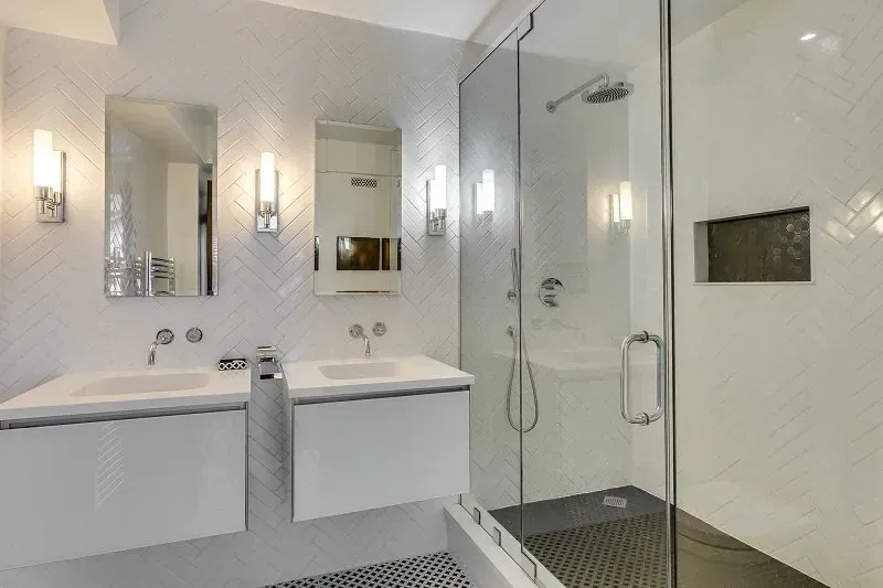 A bathroom with two sinks and a walk in shower.
