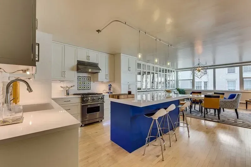 A kitchen with a blue island and white cabinets