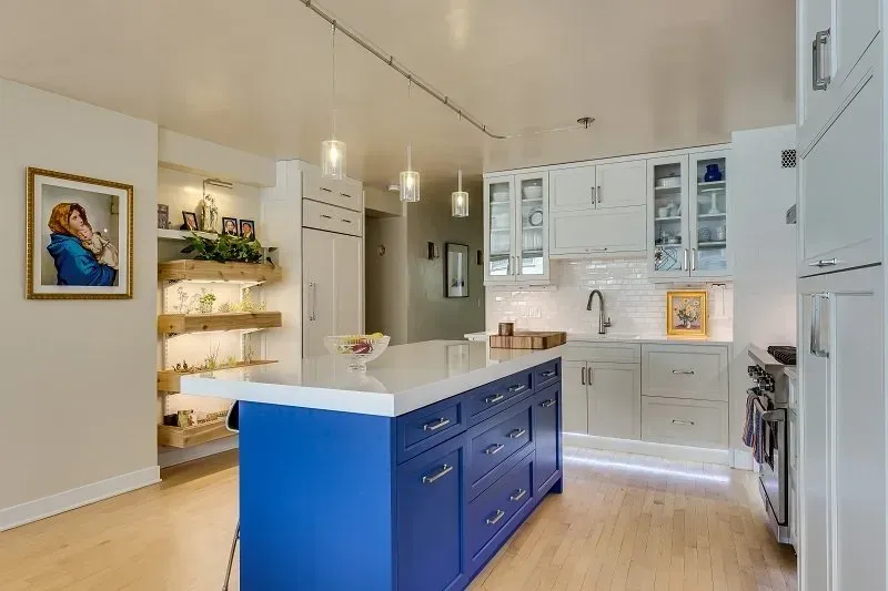 A kitchen with a blue island and white cabinets