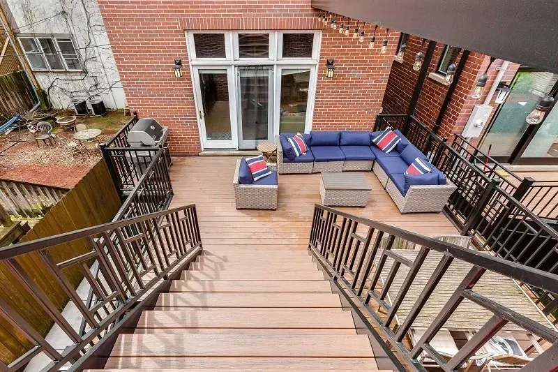 A wooden deck with a couch and stairs leading up to it.