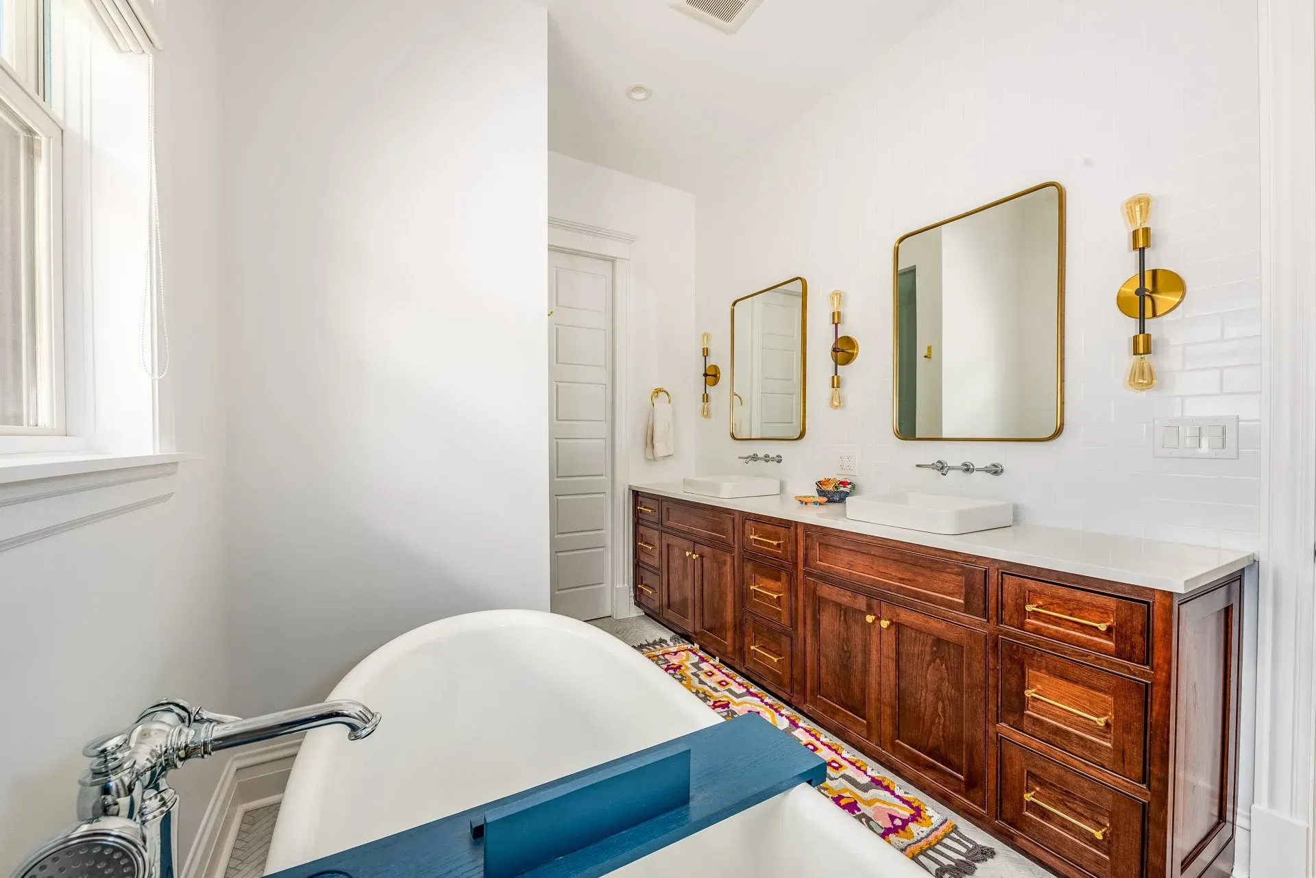 A bathroom with a blue tub , two sinks , and two mirrors.