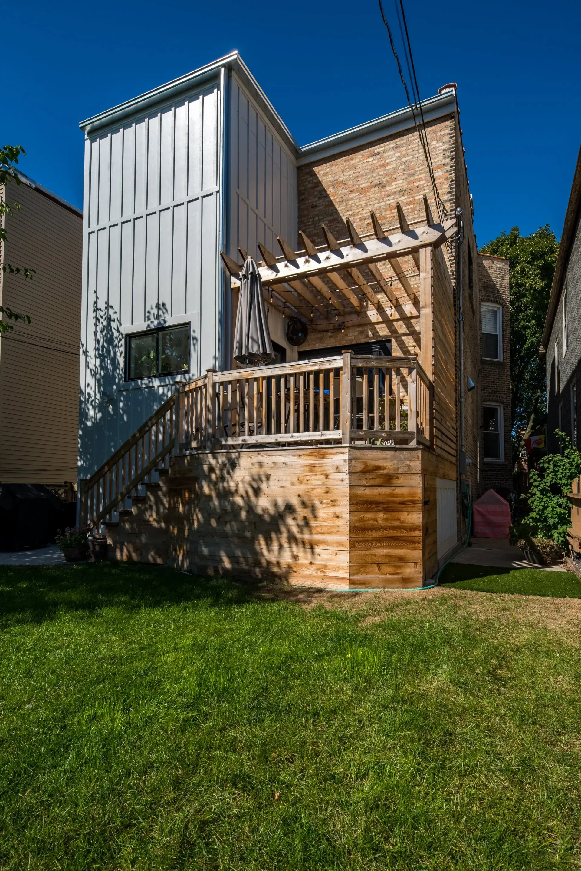 The back of a house with a wooden deck and stairs.