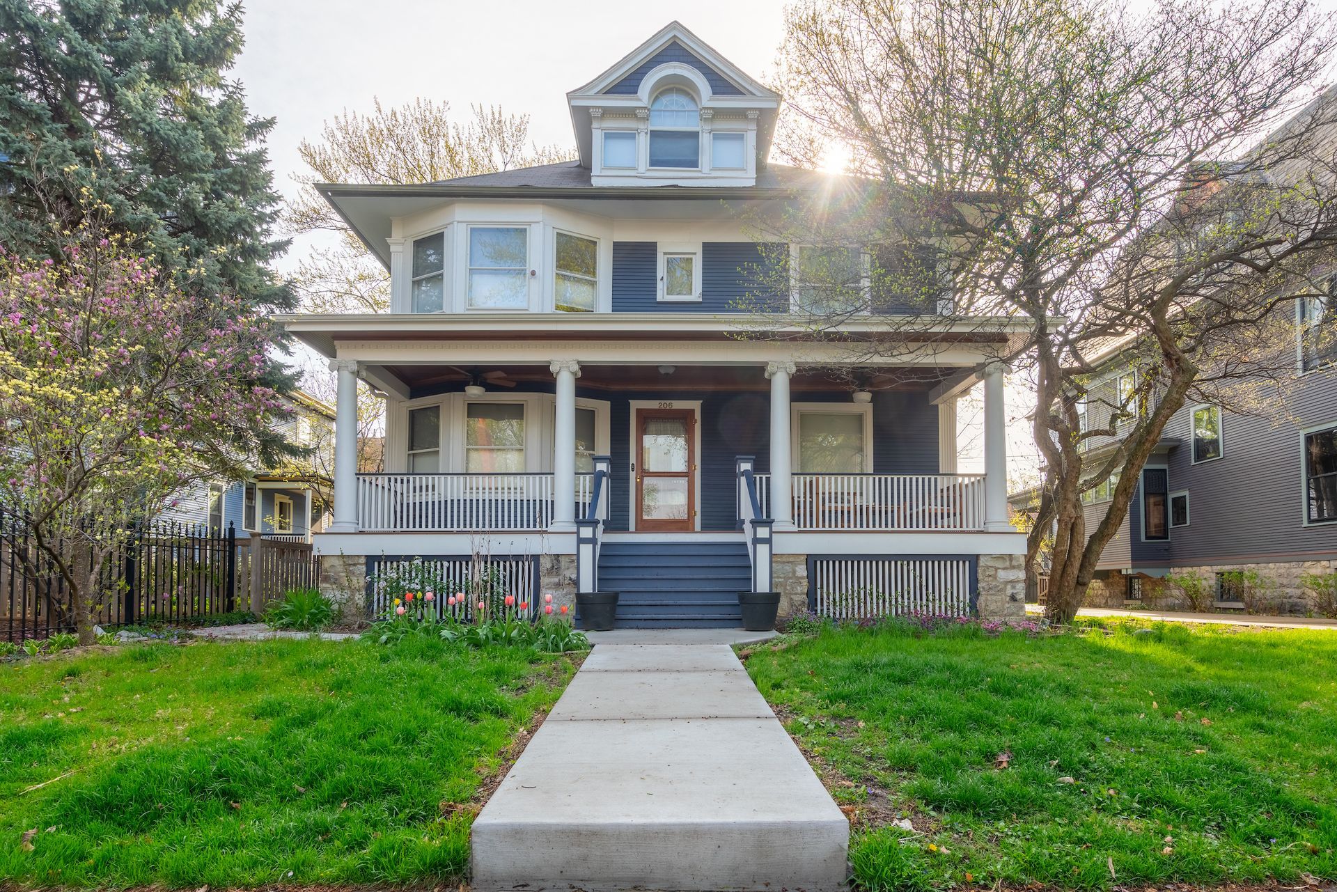 A large house with a large porch and a concrete walkway leading to it.