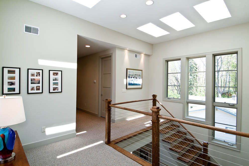A hallway with a glass railing and stairs in a house