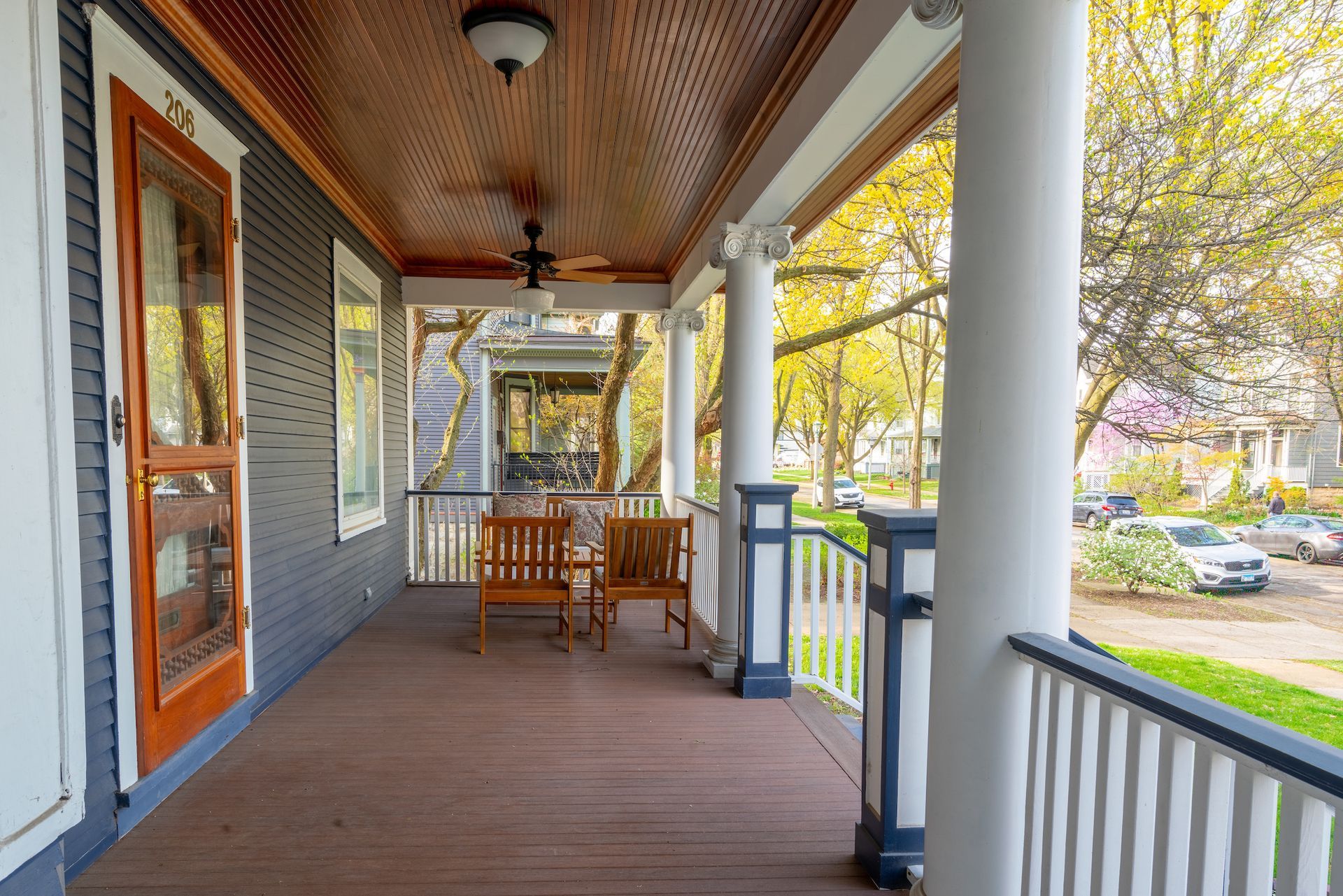 A porch with a bench and a ceiling fan on it.