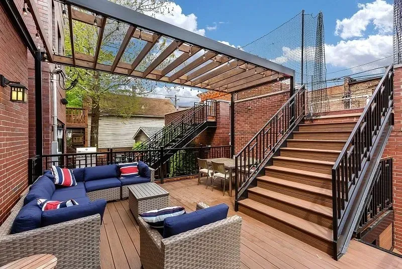 A patio with a couch and chairs and stairs leading up to it.